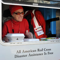 Woman in red cross van handing out food